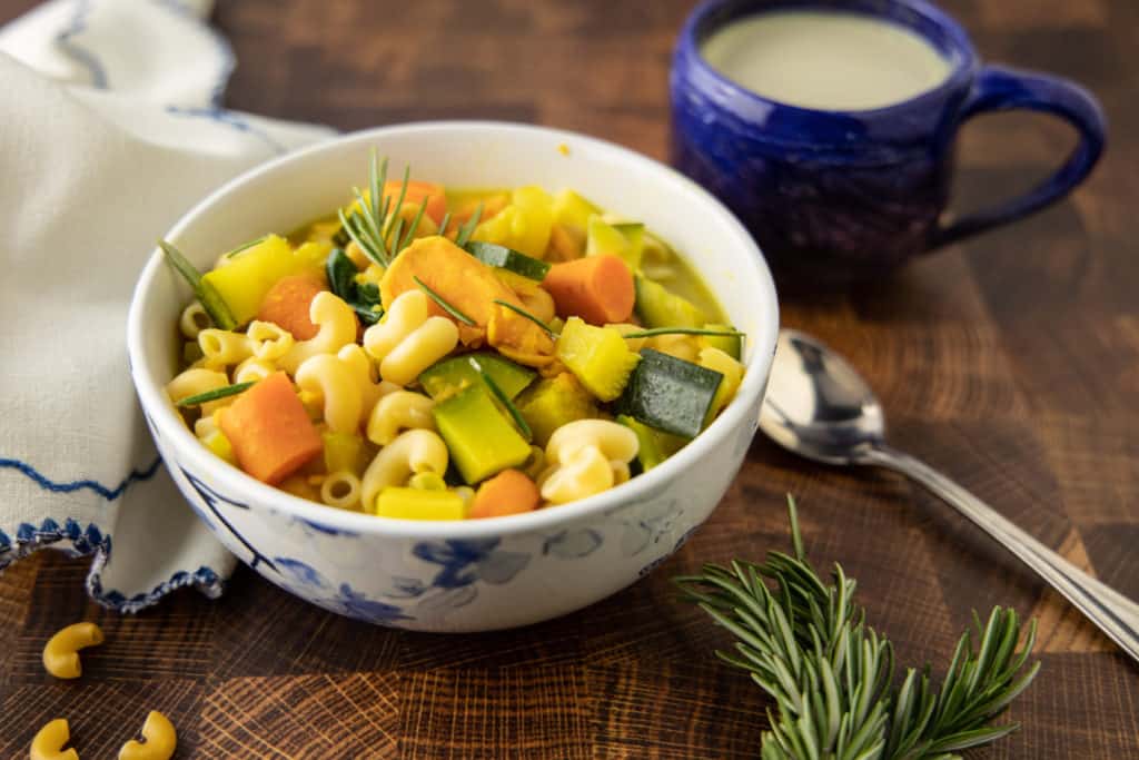 Vegan vegetable noodle soup in a bowl with herbs.